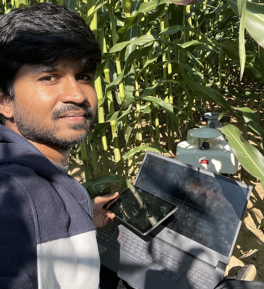 Checking a run on a tablet beside the robot, standing in a corn row at head height.